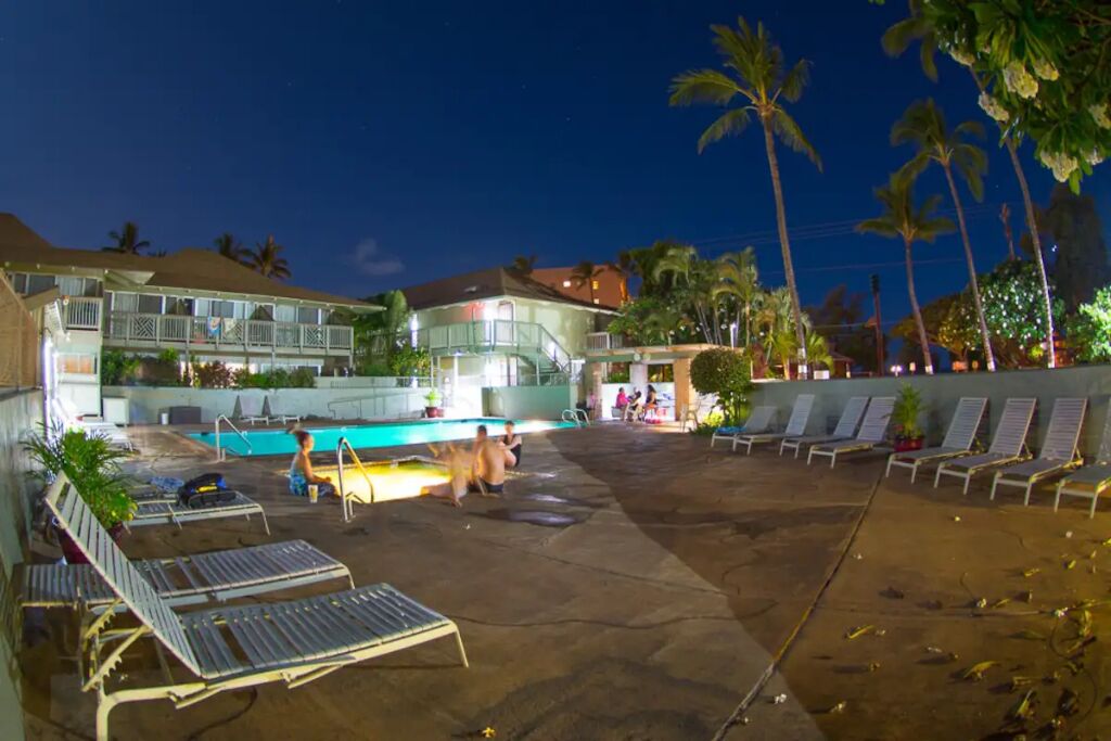 Un espace piscine comprenant des chaises longues, une piscine et un bâtiment doté de balcons.