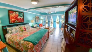 A bedroom with a large bed, a TV, and a view of the outdoors. - Tracy's Tropical Treasure #3 earned "Best in Kihei" four times and “#1 in Maui” (Kihei)