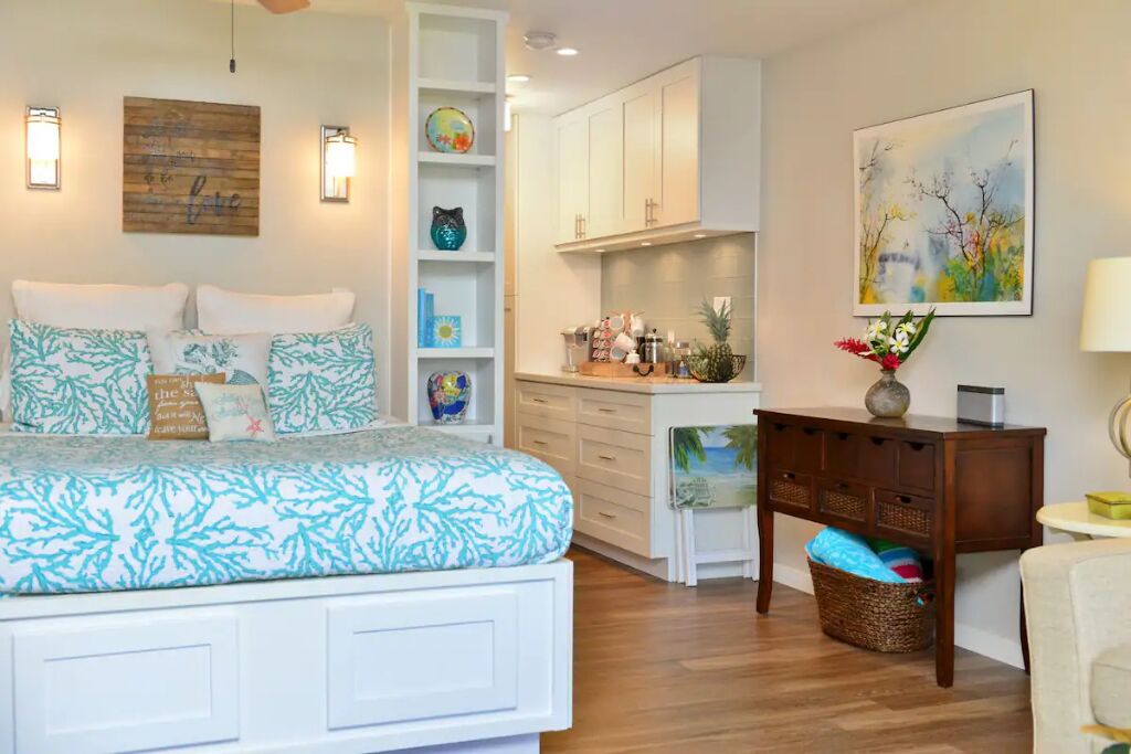 Une chambre à coucher comprenant un lit, une table de chevet, une commode et une étagère murale agrémentée d’objets décoratifs.