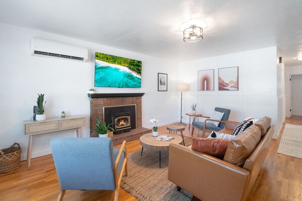Ein Wohnzimmer mit Kamin, einer Couch, einem Couchtisch und einem an der Wand befestigten Fernseher.