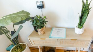 A wooden desk with a woven basket, a welcome sign, and two potted plants.