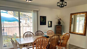 Un comedor con una mesa y sillas de madera, un espejo grande y vistas al exterior.