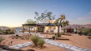 Une maison de style désertique dotée d’un patio, d’un espace salon extérieur et de cactus.