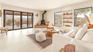 Un vaste espace de vie comprenant une grande porte-fenêtre coulissante, une cheminée, un canapé et une table basse.
