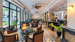 A spacious lobby with wicker furniture, large windows, and ceiling fans.