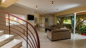 A spacious living area with a marble staircase, a sofa set, and a large window with a view of greenery. - Hotel Elotia (Chania)