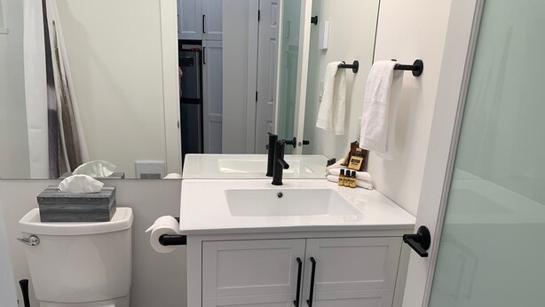 Un baño moderno con lavamanos, inodoro y tocador blancos.