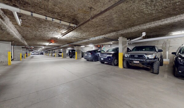 A multi-level underground parking garage with concrete pillars and a tiled floor.