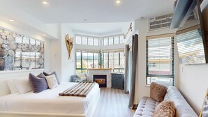 Un dormitorio moderno con una cama grande, un sofá, una chimenea y vistas al exterior.