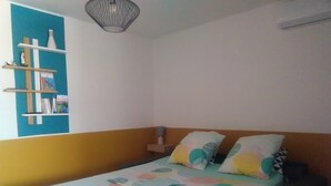 Ett sovrum med en säng, kuddar, en hylla med böcker och en hängande lampa.