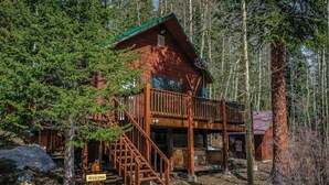 A wooden cabin with a balcony and a staircase leading to the entrance.
