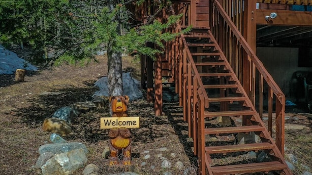 A wooden staircase leading to a cabin, surrounded by rocks and a 'Welcome' sign.