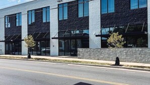 A modern building with a flat roof, large windows, and a clean, straight road in front.