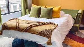 A modern bedroom with a large bed, two side tables, a window with curtains, and a unique wall decoration.