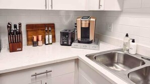 A kitchen with white cabinets, a coffee maker, a toaster, and a knife block.