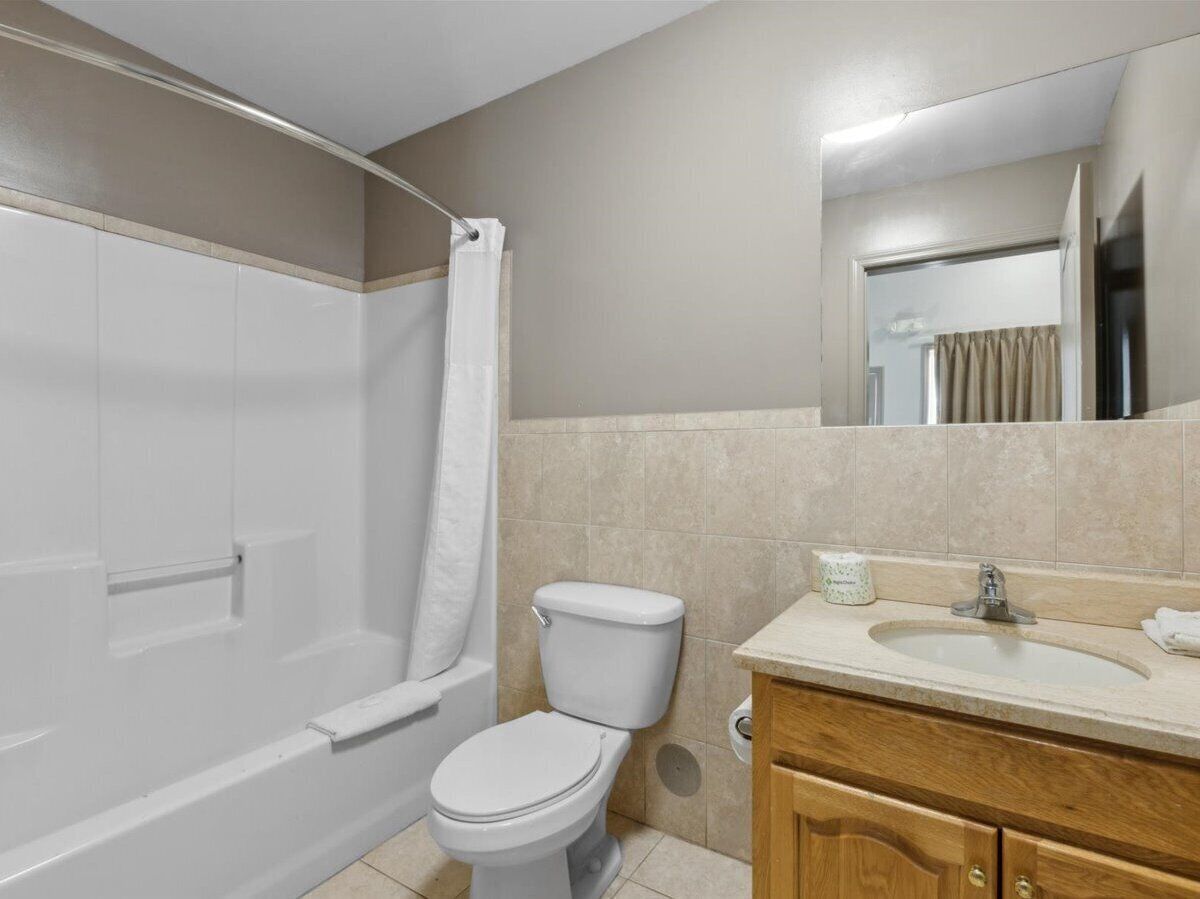 A bathroom with a bathtub, toilet, sink, and mirror.