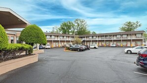 Un motel con estacionamiento, varios coches y un edificio de techo plano y balcones.
