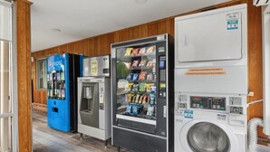 Un cuarto de lavandería con lavadora, máquina expendedora y refrigerador.