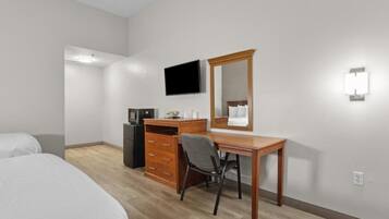 Une chambre d’hôtel comprenant un lit, un bureau avec une chaise, une commode, une télévision et un miroir.