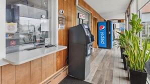 Zona de recepción de un hotel con mostrador, cajero automático y refrigerador de Pepsi.
