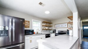 A modern kitchen with stainless steel appliances, white cabinetry, and a central island.
