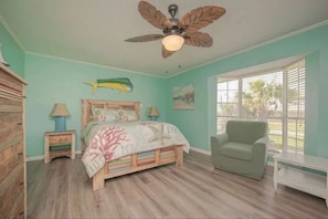 Une chambre à coucher avec un lit, un ventilateur de plafond, une chaise et une fenêtre.
