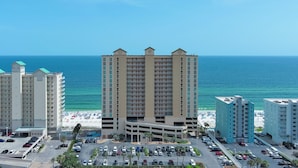 A high-rise hotel with a parking lot and a beach view. - Crystal Shores West 403 - BEACH FRONT | Zero Entry Pool, Indoor Pool, Hot Tub, Sauna, Fitness (Gulf Shores)
