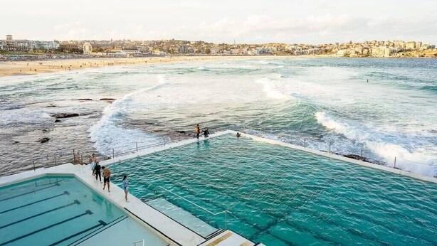 A coastal swimming area with a pool and beach in the background.