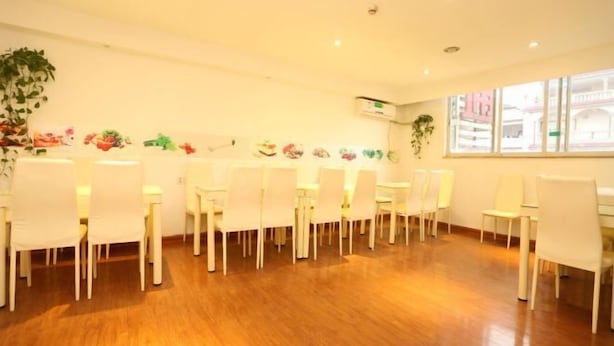 Un salón de conferencias con sillas y mesas blancas, suelo de madera y decoración en las paredes.