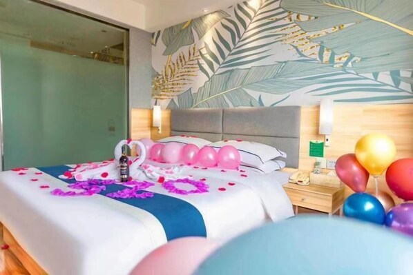 A hotel room with a bed, a nightstand, and a wall with a leaf pattern.