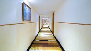 Passadís allargat i estret d'un hotel, amb una catifes amb disseny, parets blanques i una obra d'art emmarcada a la paret esquerra.