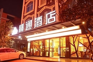 Un hotel con un letrero, un coche estacionado al frente y una entrada bien iluminada.
