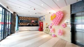 Un vestíbulo de hotel con una recepción, un adorno de globo con forma de corazón y una decoración de diseño moderno.