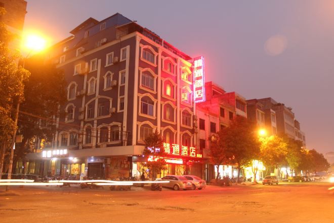 Un hotel de varios pisos con un llamativo letrero de neón rojo en la planta baja.