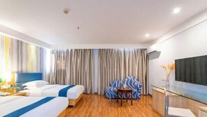 Habitación de hotel con dos camas, un sofá, un televisor y un escritorio.