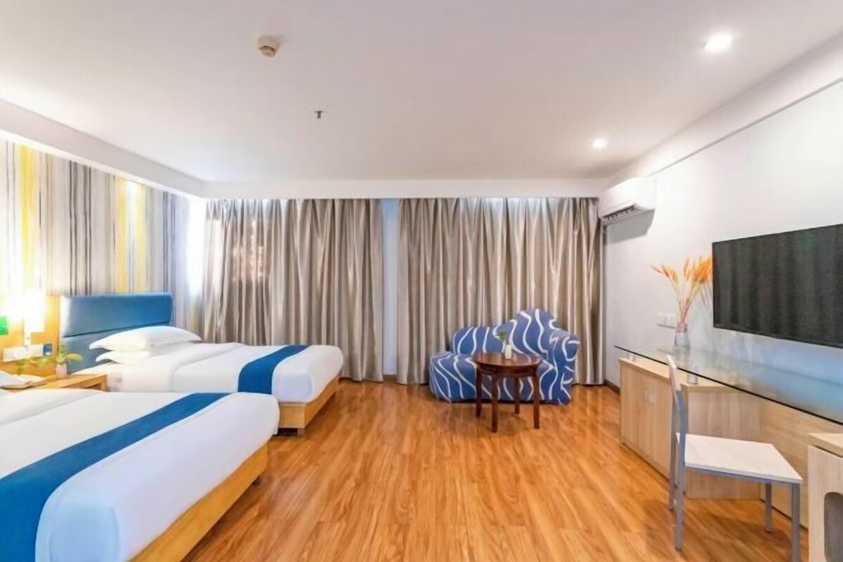 Habitación de hotel con dos camas, un sofá, un televisor y un escritorio.