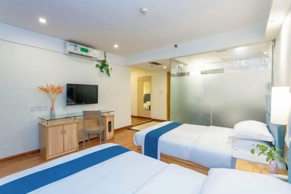 Habitación de hotel con dos camas, un escritorio, un televisor y un espejo.