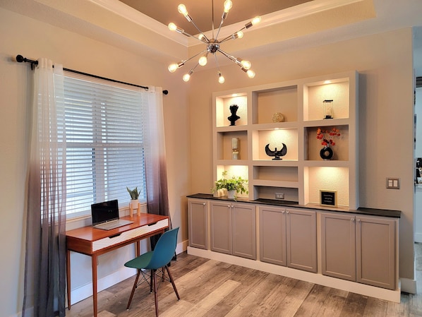 A modern kitchen with a wooden countertop, a dining area with a table and chairs, and a ceiling light fixture.