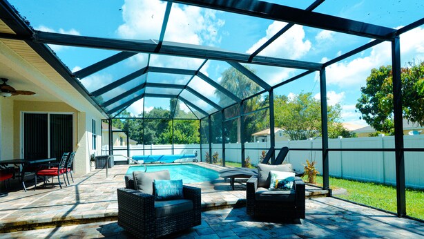 Eine überdachte Terrasse mit Pool, Gartenmöbeln und Blick auf den Hinterhof.
