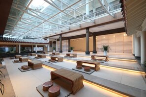 A spacious lobby with a high ceiling, modern furniture, and a central seating area. - Qiqushan Hotel (Zitong)
