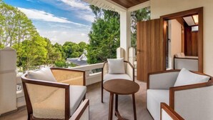 A balcony with wicker furniture and a round table, overlooking a lush green landscape. - Qiqushan Hotel (Zitong)