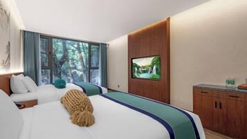 A hotel room with a large bed, a TV on the wall, a wooden cabinet, and a window with a view of trees.