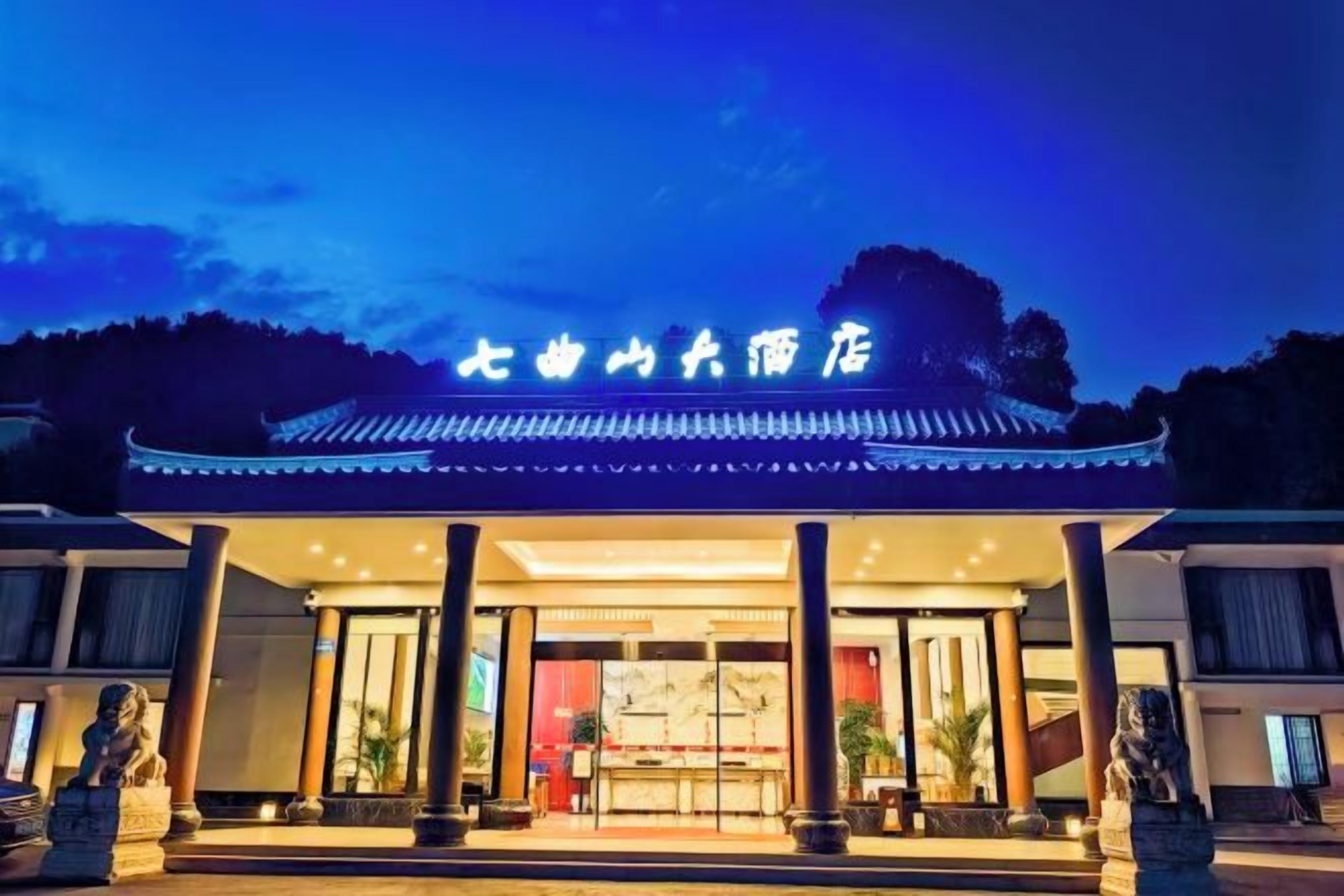 A traditional Chinese building with a sign, large columns, and a tiled roof.