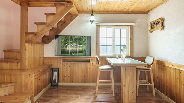 A wooden interior with a staircase, a dining area with a table and chairs, a television mounted on the wall, and a window with a view of greenery. - Ganghwa Gichayeohaeng Pension (Incheon)