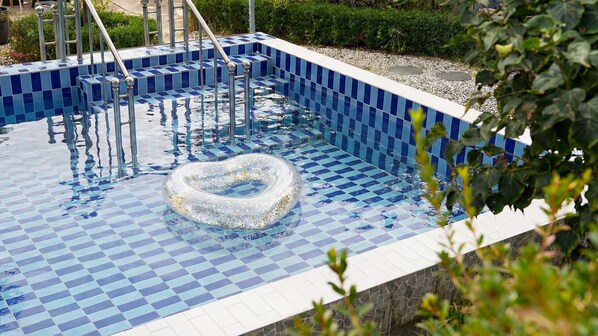 Ein Swimmingpool mit einem herzförmigen Schwimmpfädchen und blauen Schachbrettfliesen.
