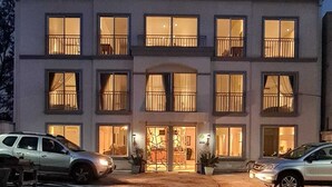 A multi-story hotel with a central entrance, balconies on each floor, and a parking area in front. - LOP Inn (La Asunción)