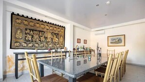 A spacious dining area with a large table and multiple chairs, a decorative wall hanging, and framed pictures on the walls. - LOP Inn (La Asunción)