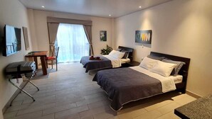 A hotel room with two beds, a desk, a chair, and a TV. - LOP Inn (La Asunción)