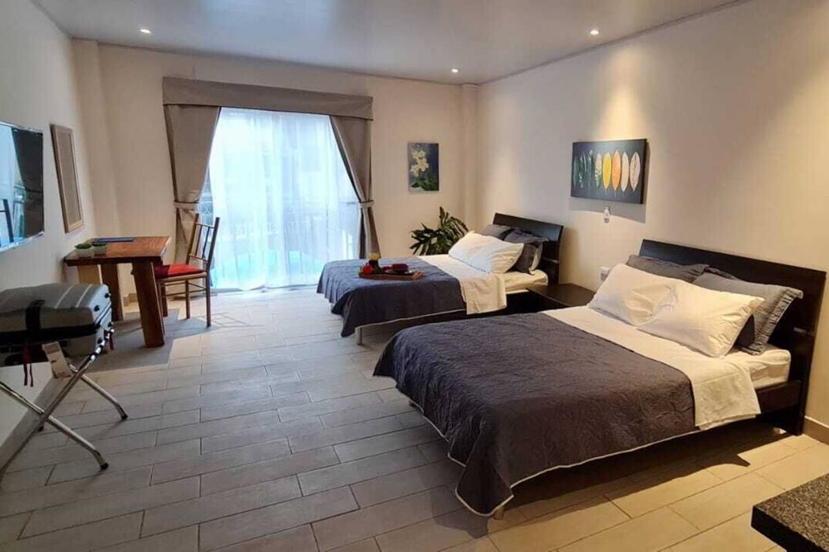 A hotel room with two beds, a desk, a chair, and a TV.