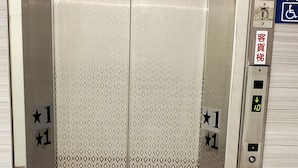 An elevator with a metallic finish, featuring a patterned design on the doors and a control panel with a wheelchair accessibility symbol. - Ximen Garden Hotel (Taipei)